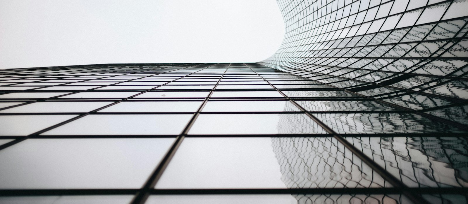 A glass and steel curtain wall photographed from below, its panels repeating in a regular grid.