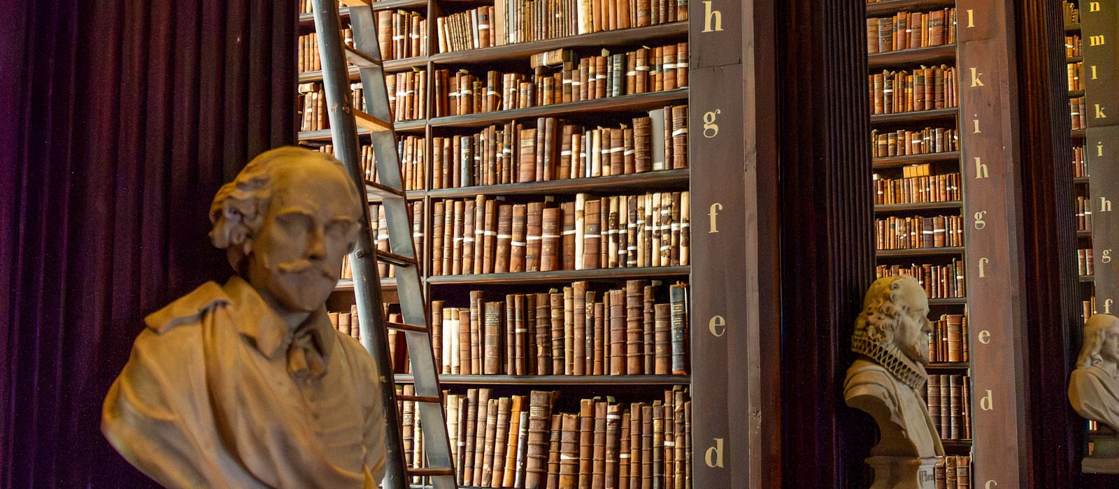 The upper galleries of a large historic library, shelves rising several storeys.